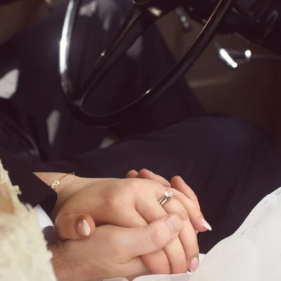 Bride and groom holding hands in car