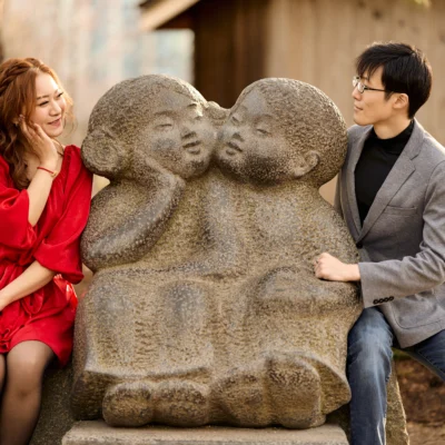 Guy and girl sitting next to a statue Kariya Park Engagement Photoshoot