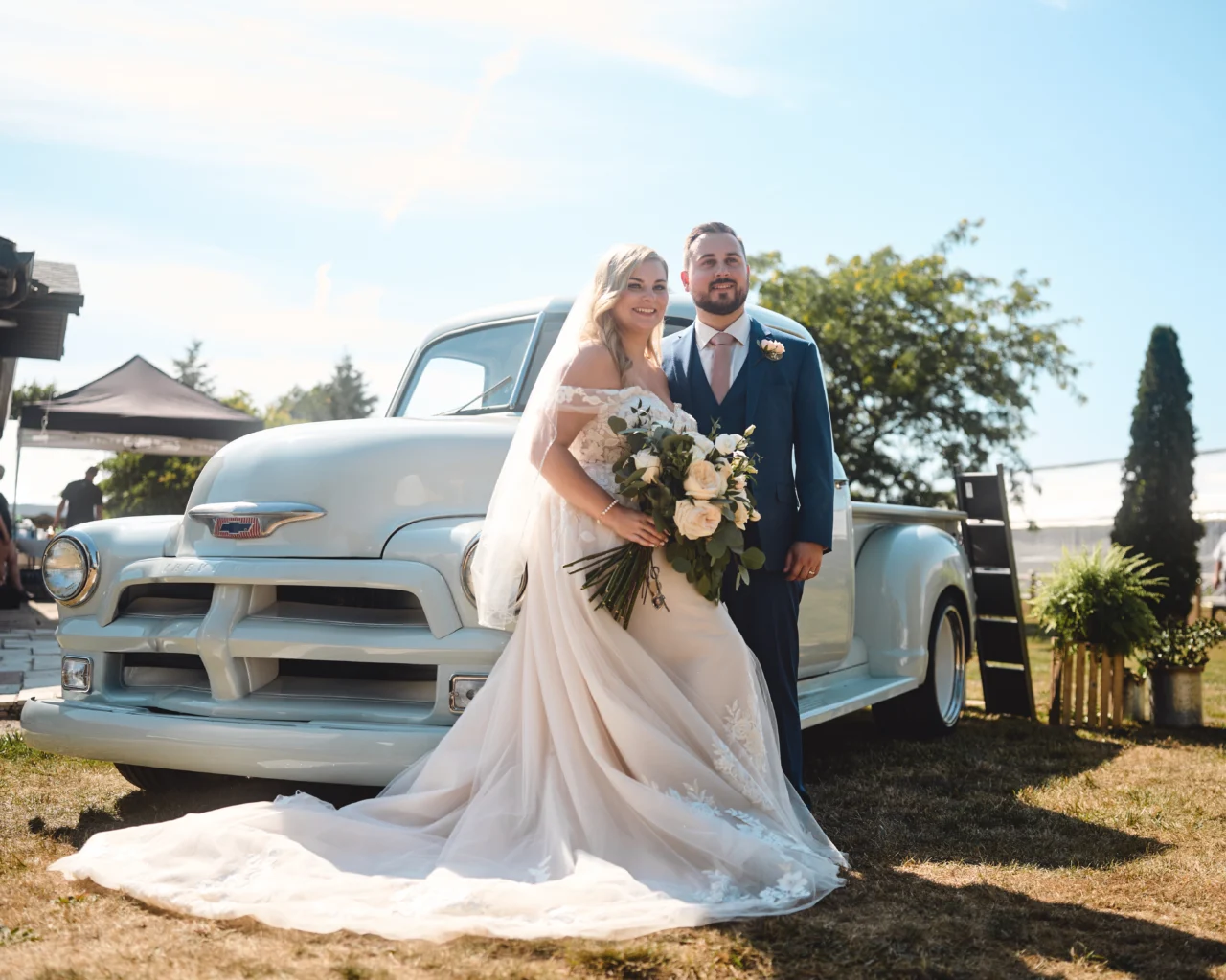Outdoor wedding portrait of bride and groom beside the car