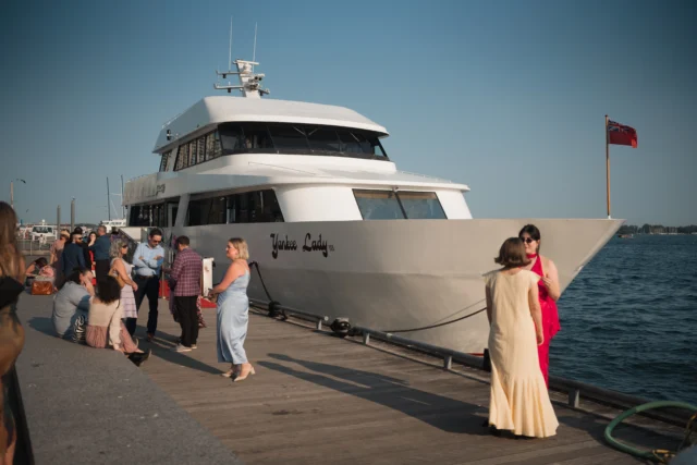 White yacht docked with people on around it