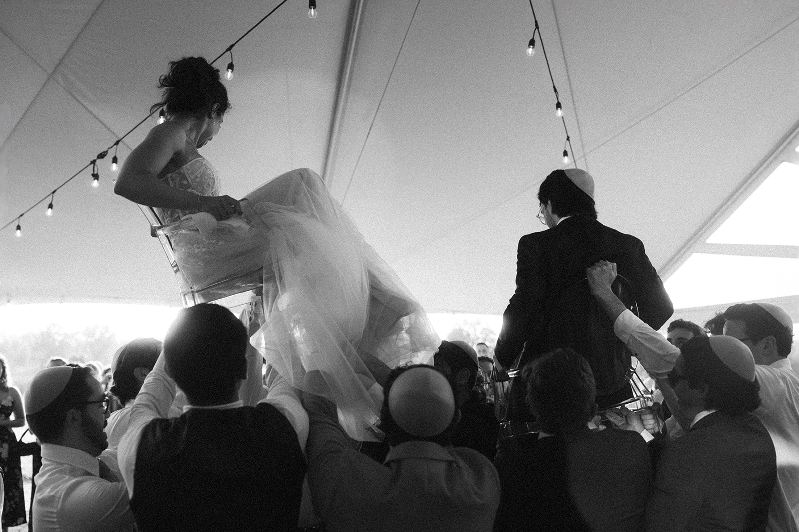 bride and groom on chairs during hora
