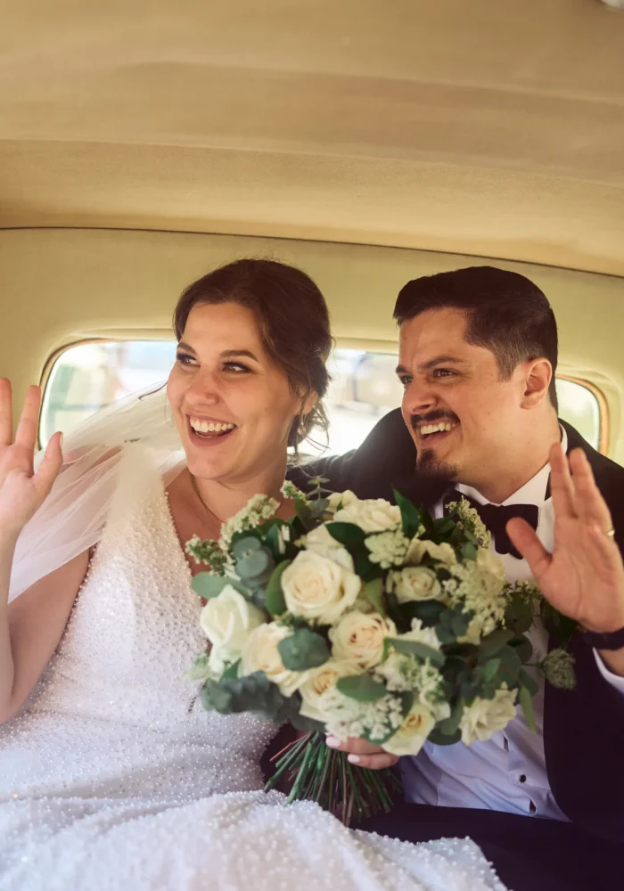 Bride and groom waving at people