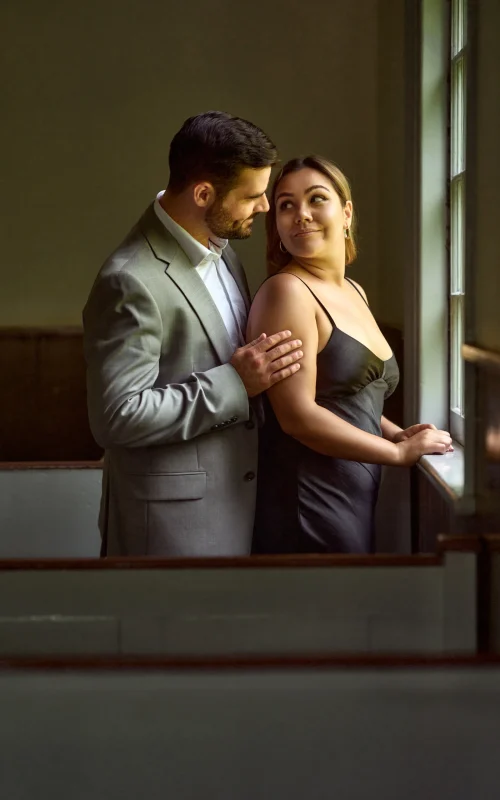 Guy holding girl next to a window Black Creek Village Engagement Photoshoot
