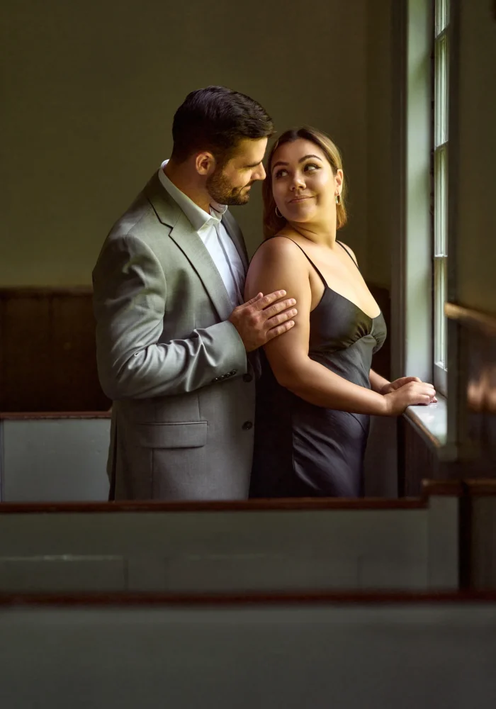 Guy holding girl next to a window Black Creek Village Engagement Photoshoot