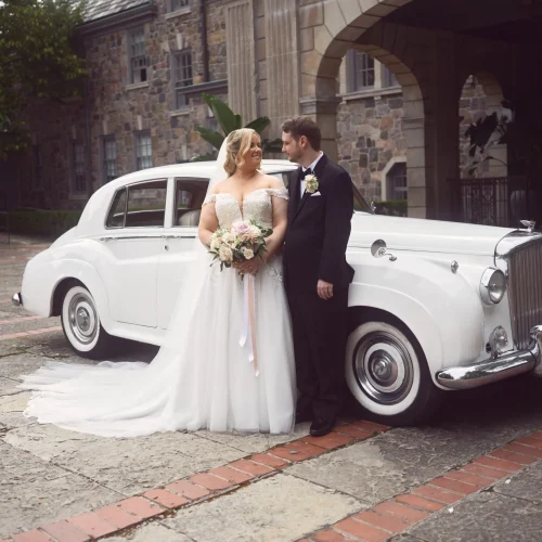 Wedding day outdoor moment with bride and groom near the car